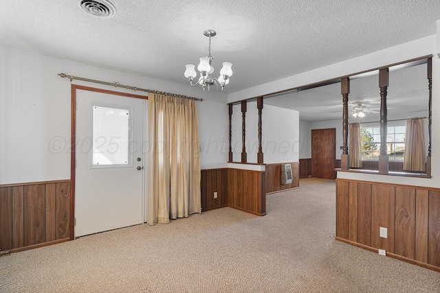 foyer featuring visible vents, a textured ceiling, wood walls, and wainscoting