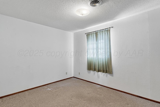 carpeted spare room featuring baseboards, visible vents, and a textured ceiling