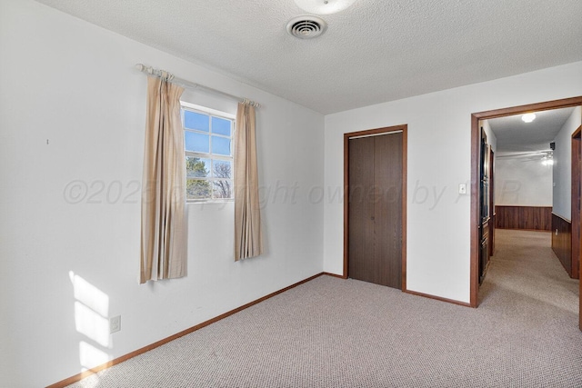 unfurnished bedroom with visible vents, baseboards, carpet floors, a closet, and a textured ceiling