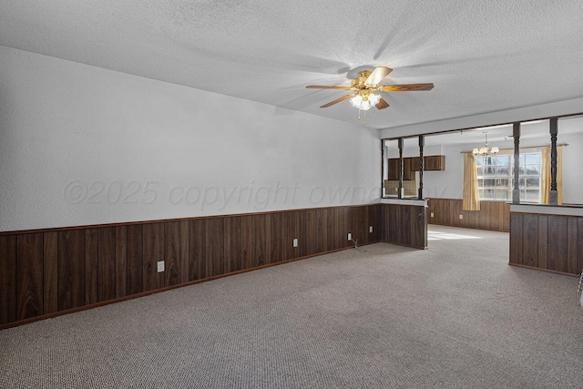 unfurnished living room featuring a wainscoted wall, wood walls, a textured ceiling, and carpet flooring