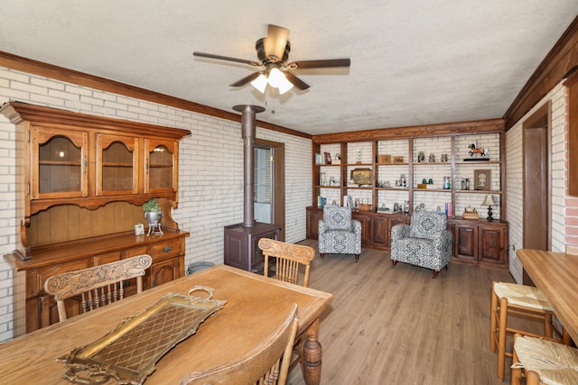 dining room with light wood-type flooring, brick wall, and a wood stove