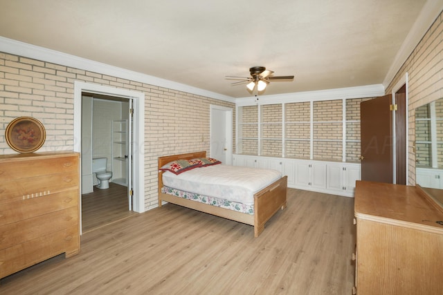 bedroom featuring ornamental molding, brick wall, light hardwood / wood-style floors, and ensuite bath