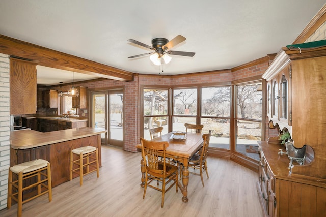 dining space with beam ceiling, light hardwood / wood-style flooring, ceiling fan, and brick wall