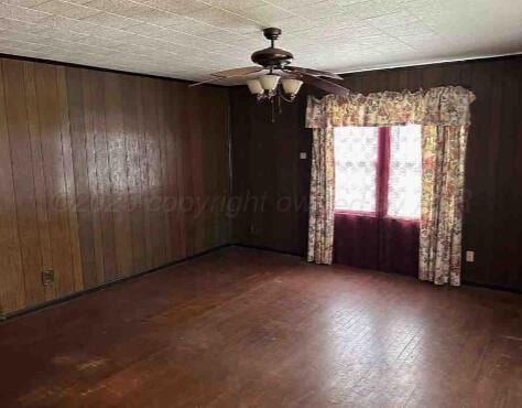 1035 N Duncan St, Pampa, TX 79065 - spare room featuring wooden walls, ceiling fan, and wood finished floors