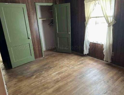 1035 N Duncan St, Pampa, TX 79065 - unfurnished bedroom with wood finished floors, a closet, and wood walls