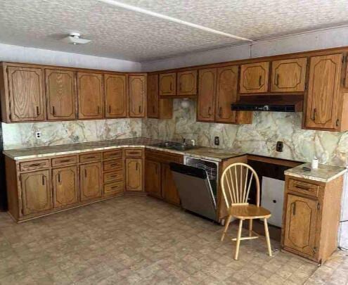 1035 N Duncan St, Pampa, TX 79065 - kitchen featuring dishwasher, under cabinet range hood, brown cabinetry, and light flooring