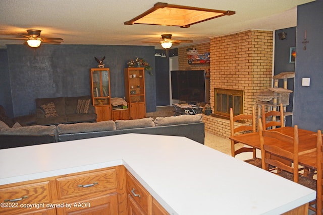 kitchen featuring ceiling fan, a textured ceiling, a skylight, and a fireplace