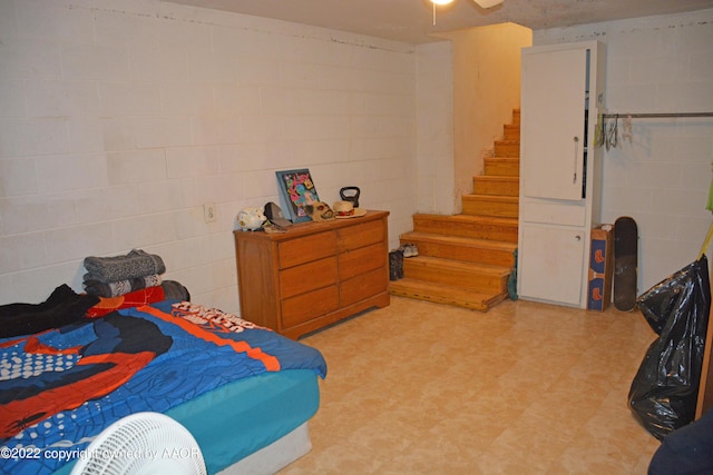 bedroom with concrete block wall and light floors
