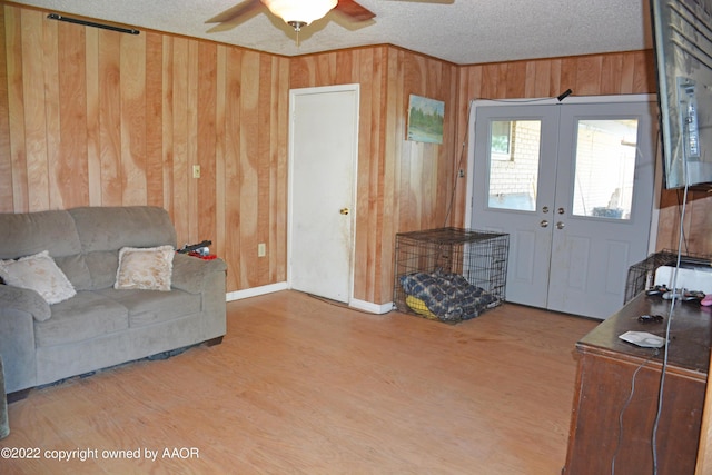 entrance foyer featuring ceiling fan, wood walls, hardwood / wood-style flooring, a textured ceiling, and french doors