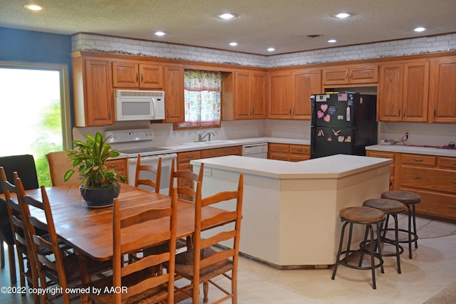 kitchen with sink, white appliances, a center island, and a textured ceiling