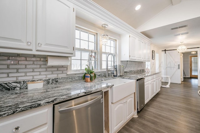 kitchen featuring lofted ceiling, a barn door, a sink, white cabinets, and dishwasher