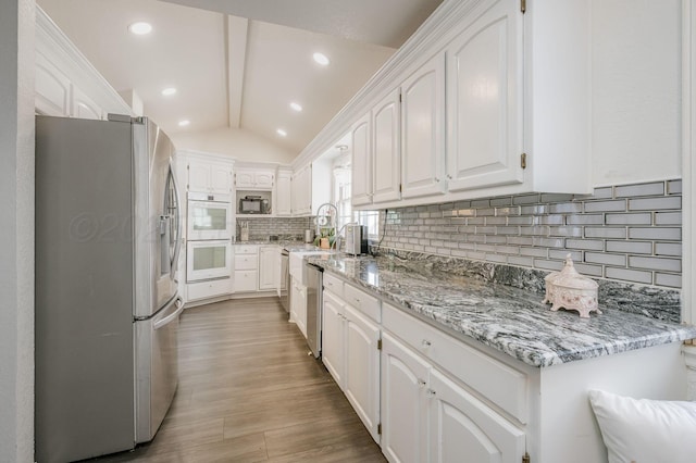 kitchen featuring stainless steel appliances, white cabinetry, and decorative backsplash