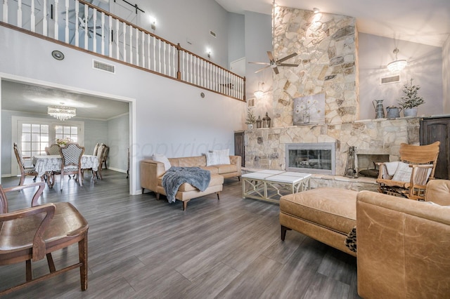 living room with a fireplace, visible vents, a towering ceiling, wood finished floors, and baseboards