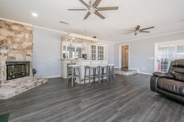 living area featuring a fireplace, visible vents, dark wood-style flooring, and crown molding