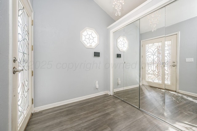 foyer with lofted ceiling, wood finished floors, and baseboards