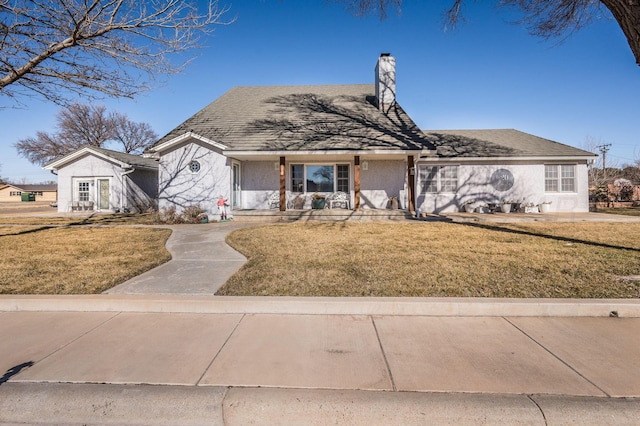 view of front facade featuring a front yard, a chimney, and stucco siding