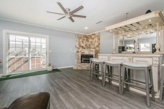 dining space featuring a fireplace, baseboards, crown molding, and wood finished floors