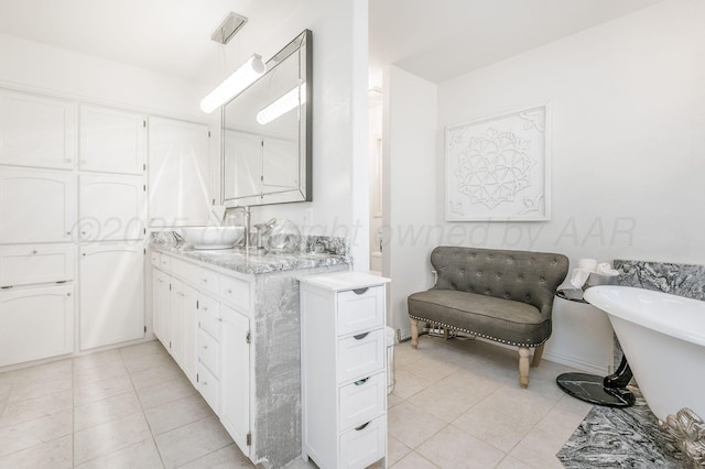 full bath featuring a freestanding tub, vanity, and tile patterned floors