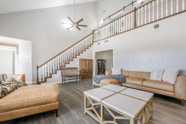 living room featuring visible vents, stairway, a high ceiling, and wood finished floors