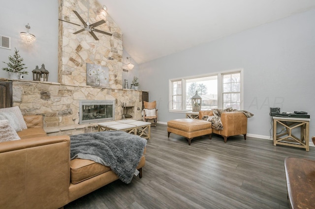 living area with baseboards, visible vents, wood finished floors, a stone fireplace, and high vaulted ceiling