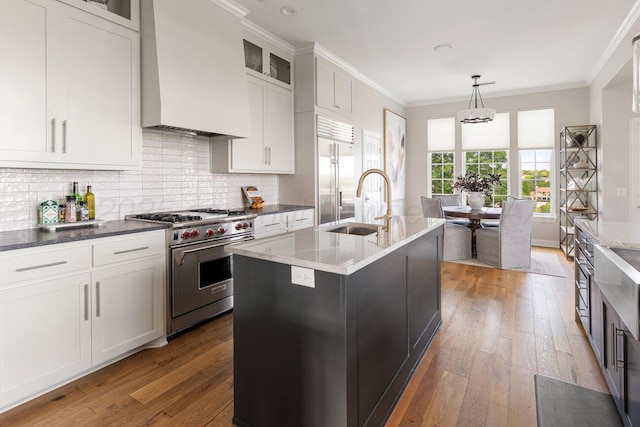 27 Carnoustie Ln, Amarillo, TX 79124 - kitchen featuring premium appliances, premium range hood, ornamental molding, hardwood / wood-style flooring, and backsplash
