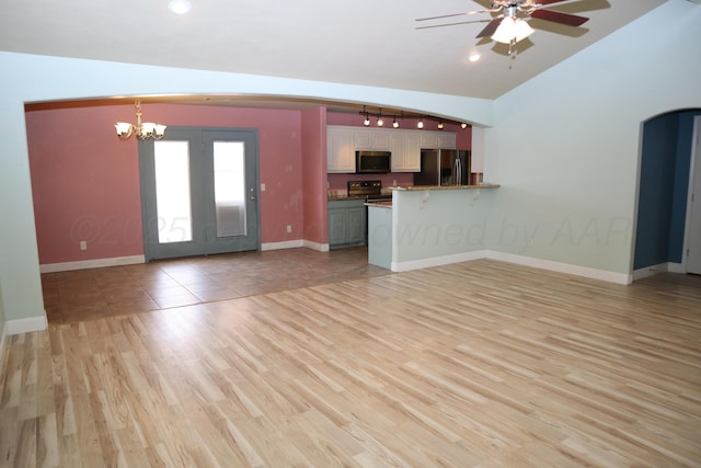 9807 Will Ave, Amarillo, TX 79119 - unfurnished living room with a chandelier, ceiling fan, light wood-style flooring, vaulted ceiling, and arched walkways