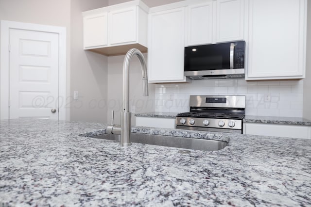 10502 Ruse St, Amarillo, TX 79118 - kitchen with appliances with stainless steel finishes, white cabinetry, backsplash, and light stone countertops