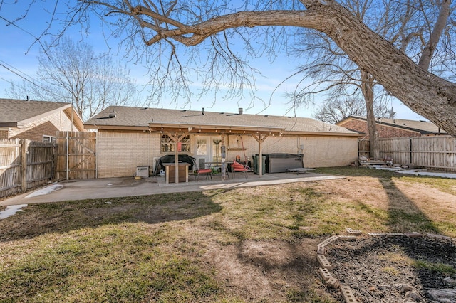 back of property with a patio area, a hot tub, and a yard