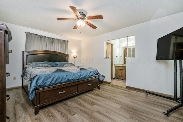 bedroom featuring light wood-type flooring, ceiling fan, a textured ceiling, and ensuite bath