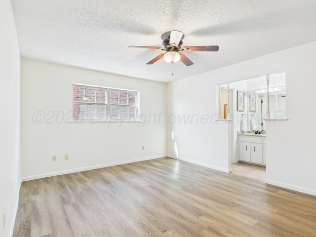 empty room with light wood finished floors, a textured ceiling, ceiling fan, and baseboards