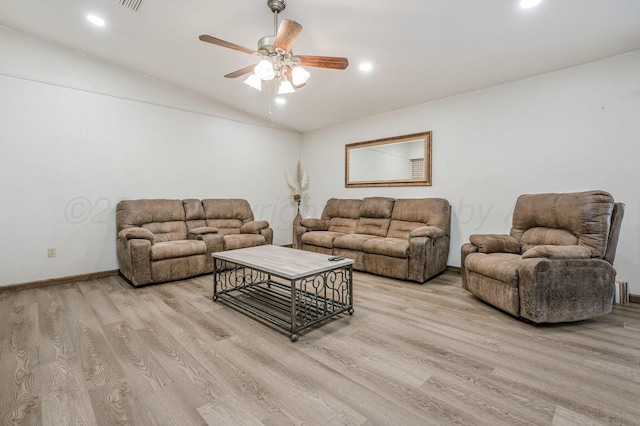 living room with ceiling fan, vaulted ceiling, and light wood-type flooring