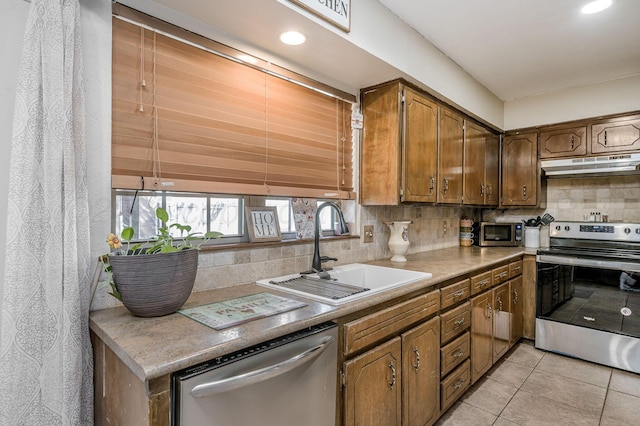 kitchen featuring light tile patterned floors, appliances with stainless steel finishes, tasteful backsplash, and sink