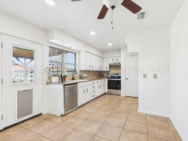 kitchen with visible vents, under cabinet range hood, a sink, stainless steel appliances, and decorative backsplash
