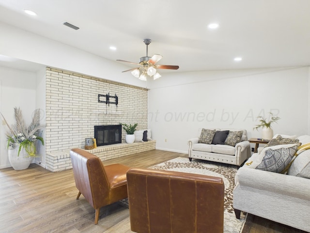 living area featuring ceiling fan, visible vents, recessed lighting, wood finished floors, and a brick fireplace