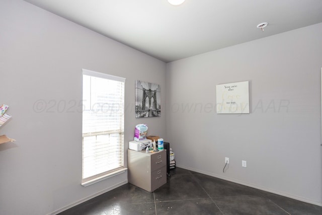 unfurnished office featuring baseboards and dark tile patterned flooring