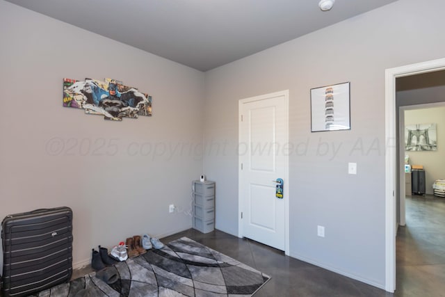 unfurnished bedroom with finished concrete flooring and baseboards