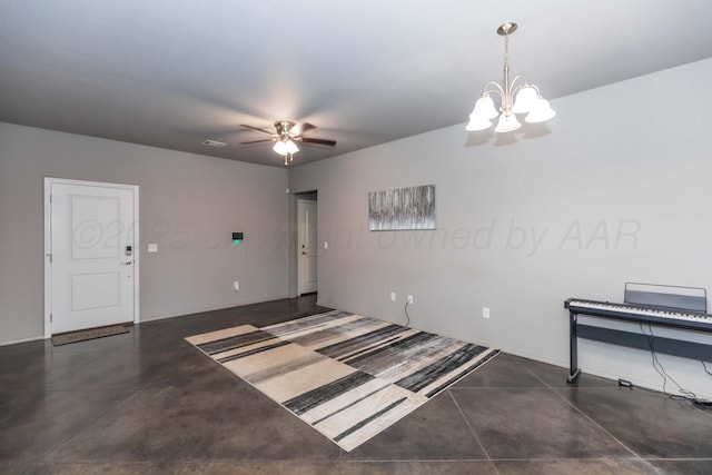 unfurnished room with concrete flooring, a chandelier, ceiling fan, and baseboards