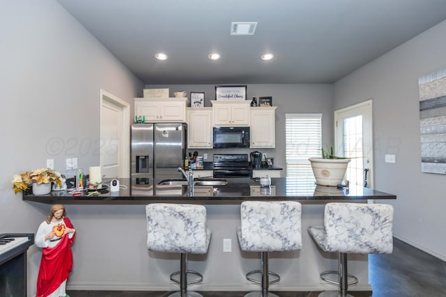 kitchen featuring black appliances, a kitchen breakfast bar, a sink, a peninsula, and recessed lighting