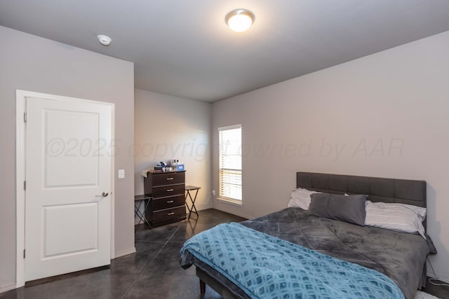 bedroom with concrete floors and baseboards
