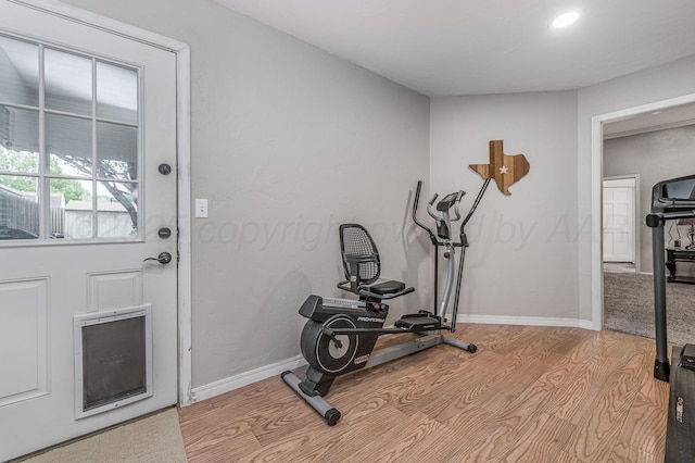 exercise room featuring baseboards, recessed lighting, and light wood-style floors