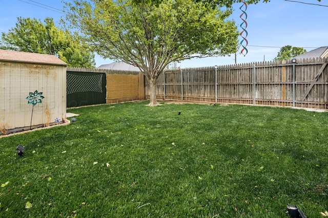 view of yard featuring a fenced backyard, a storage unit, and an outbuilding
