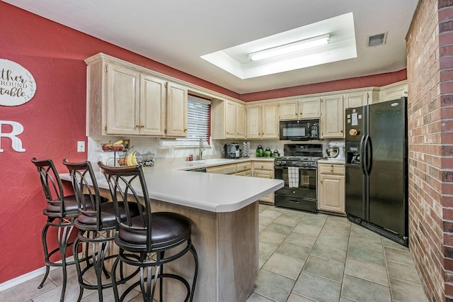 kitchen with a kitchen breakfast bar, light countertops, a sink, black appliances, and a peninsula