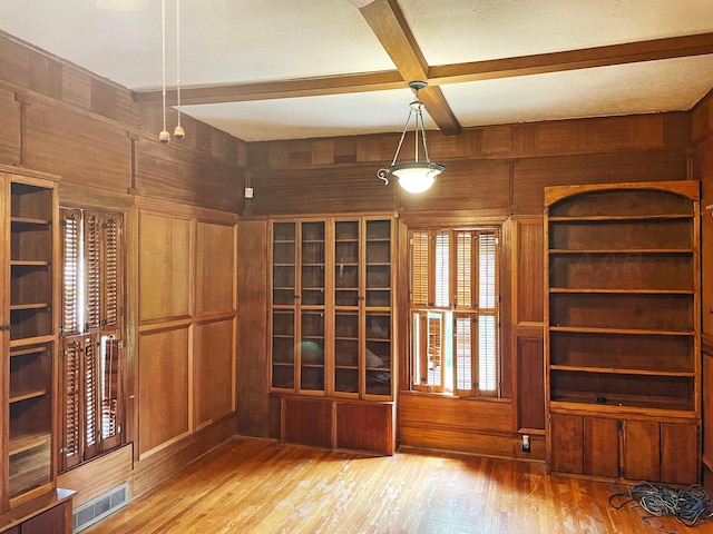 unfurnished room with a textured ceiling, beam ceiling, wood walls, coffered ceiling, and hardwood / wood-style flooring