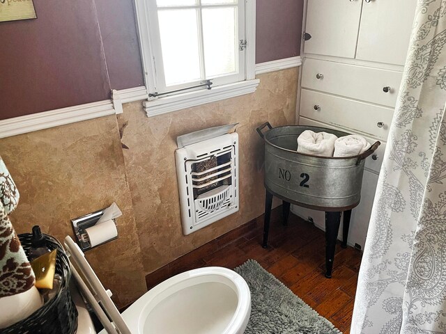 bathroom featuring hardwood / wood-style floors, heating unit, and tile walls