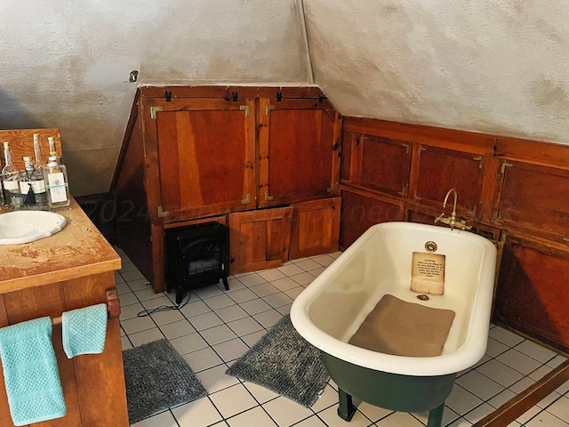 bathroom featuring tile patterned floors, a tub to relax in, a textured ceiling, and vaulted ceiling