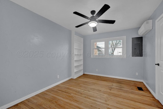 empty room with electric panel, light wood finished floors, visible vents, and an AC wall unit