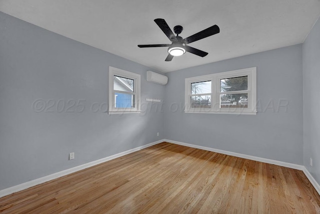 empty room with baseboards, light wood finished floors, a wall mounted AC, and plenty of natural light