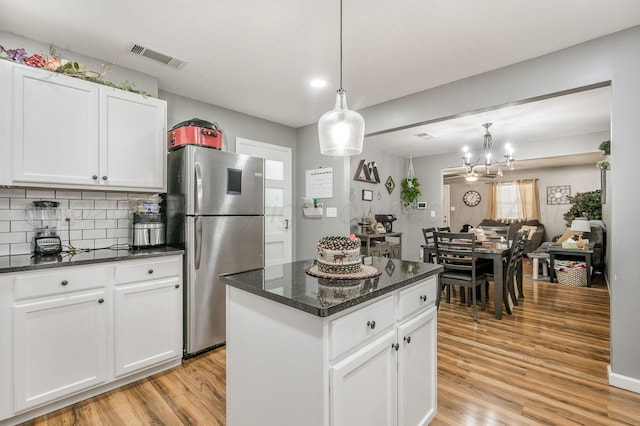 4639 S Hughes St, Amarillo, TX 79110 - kitchen with freestanding refrigerator, light wood-type flooring, a kitchen island, white cabinets, and tasteful backsplash