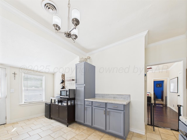 1206 N Russell St, Pampa, TX 79065 - kitchen featuring gray cabinetry, stainless steel microwave, crown molding, light countertops, and a chandelier