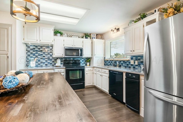 kitchen featuring white cabinetry, a sink, dark wood-type flooring, and black appliances